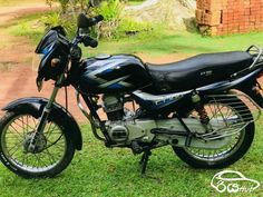 a black motorcycle parked on top of a lush green field