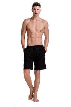 a shirtless man standing in front of a white background wearing black shorts and no shirt