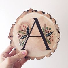 a hand holding up a piece of wood that has the letter a on it and leaves