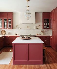 a kitchen with red cabinets and white counter tops