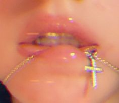 a woman with piercings on her tongue and cross necklace around her mouth, looking at the camera