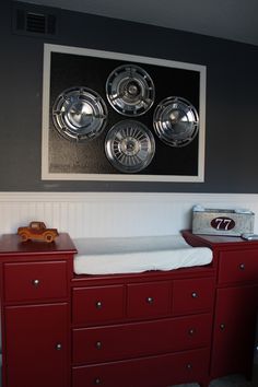 a baby's room with red dressers and pictures on the wall above them