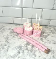 three pink candles are sitting next to each other on a marble countertop in front of a white tiled wall