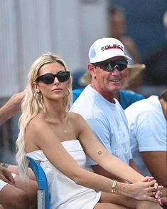 a man and woman sitting next to each other at a tennis match in the sun