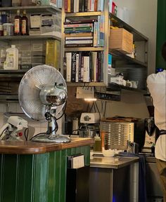 a fan sitting on top of a wooden counter next to a book shelf filled with books