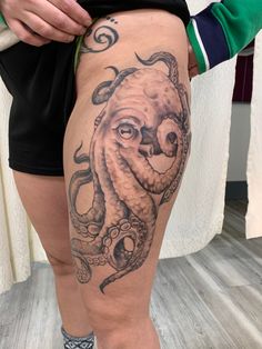 an octopus tattoo on the thigh of a woman's leg, with her legs crossed