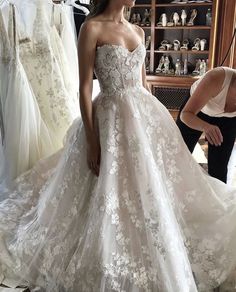 a woman standing in front of a wedding dress