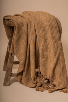 a blanket draped over a wooden chair with pom poms