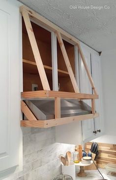 a kitchen with white cabinets and an open shelf above the stove top that is being built into the wall