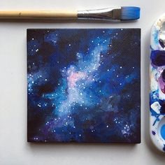 a paintbrush next to a painting on a white surface with blue and purple colors