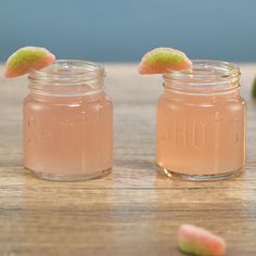 two jars filled with liquid sitting on top of a wooden table