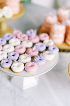 there are many different types of donuts on the table and one is pink, purple, and white