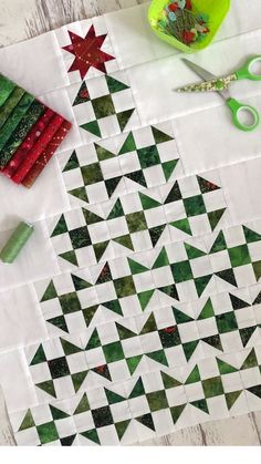 a quilted christmas tree with scissors and other crafting supplies next to it on a table