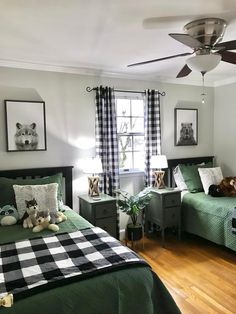 two beds in a room with green covers and plaid blankets on them, one has a stuffed animal