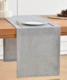 a place setting on a wooden table with silverware and napkins in front of it