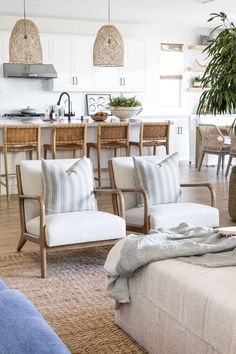 a living room filled with furniture next to a kitchen and dining room table in front of an island