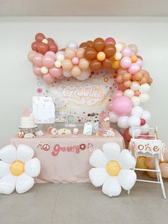 a table topped with balloons and flowers on top of a floor next to a wall