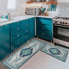 a kitchen with teal cabinets and white counter tops is pictured in this image, there are two rugs on the floor next to the stove