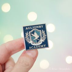 a lapel badge with the words aglionby academy on it in front of a blurry background