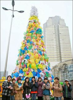 a group of people standing in front of a very large christmas tree that is decorated