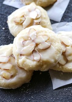 three cookies with white icing and almonds on top