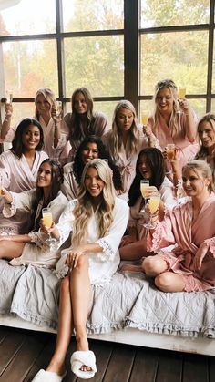 a group of women sitting on top of a bed in front of a large window