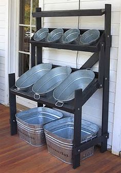 three metal buckets are stacked on top of a black rack in front of a white house