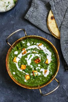 a pan filled with spinach and rice on top of a table next to some pita bread