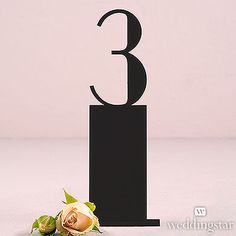 there is a black number three on top of a cake stand with a single rose