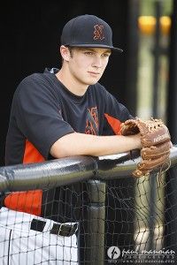 a young baseball player leaning on the fence