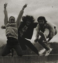 three young people jumping in the air with their arms up and one person holding his hands out