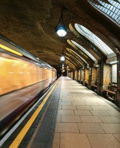 the train is moving through the station with its lights on and it's motion blurry