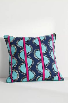 a blue and pink pillow sitting on top of a bed