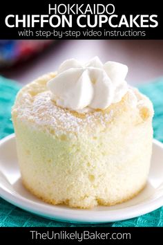 a white plate topped with a small cake covered in whipped cream on top of a blue table cloth