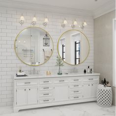 a bathroom with two round mirrors above the sinks and white counter tops on both sides