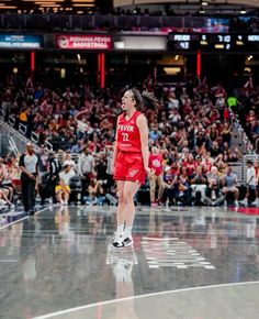 a woman in a red uniform is walking on the basketball court while people are watching