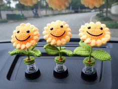 three crocheted sunflowers sitting on top of a car's dashboard