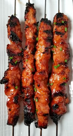 several skewers of meat on a white plate