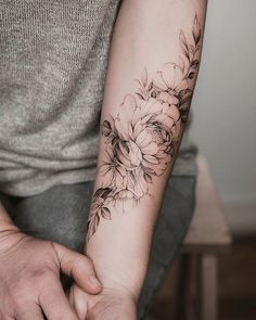 a man with a flower tattoo on his arm and wrist is holding the hand of another person