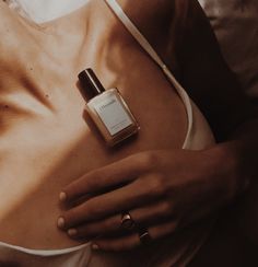 a woman laying in bed with her breast exposed and bottle of perfume next to her