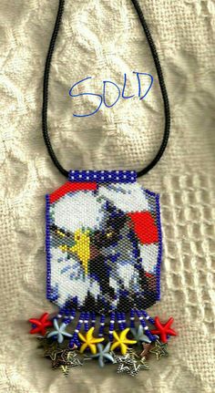 a cross stitch necklace with an eagle and stars on it