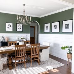 a dining room with green walls and pictures on the wall