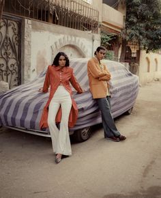 two people standing next to an old car