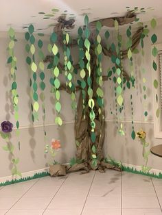 a room decorated in green and white with paper flowers on the wall, trees hanging from the ceiling