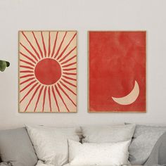 two paintings hang on the wall above a couch in a room with white walls and pillows