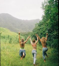 three people running up a hill with their arms in the air