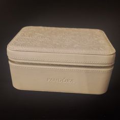 a white leather box with zippers on the front and side, sitting on a black surface