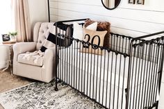 a baby's room with a black metal crib and white rugs on the floor