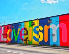 the word love is spelled in multicolored letters on a wall next to an empty street