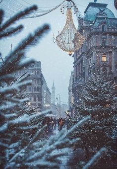 christmas decorations hanging from the side of a building on a city street in the snow